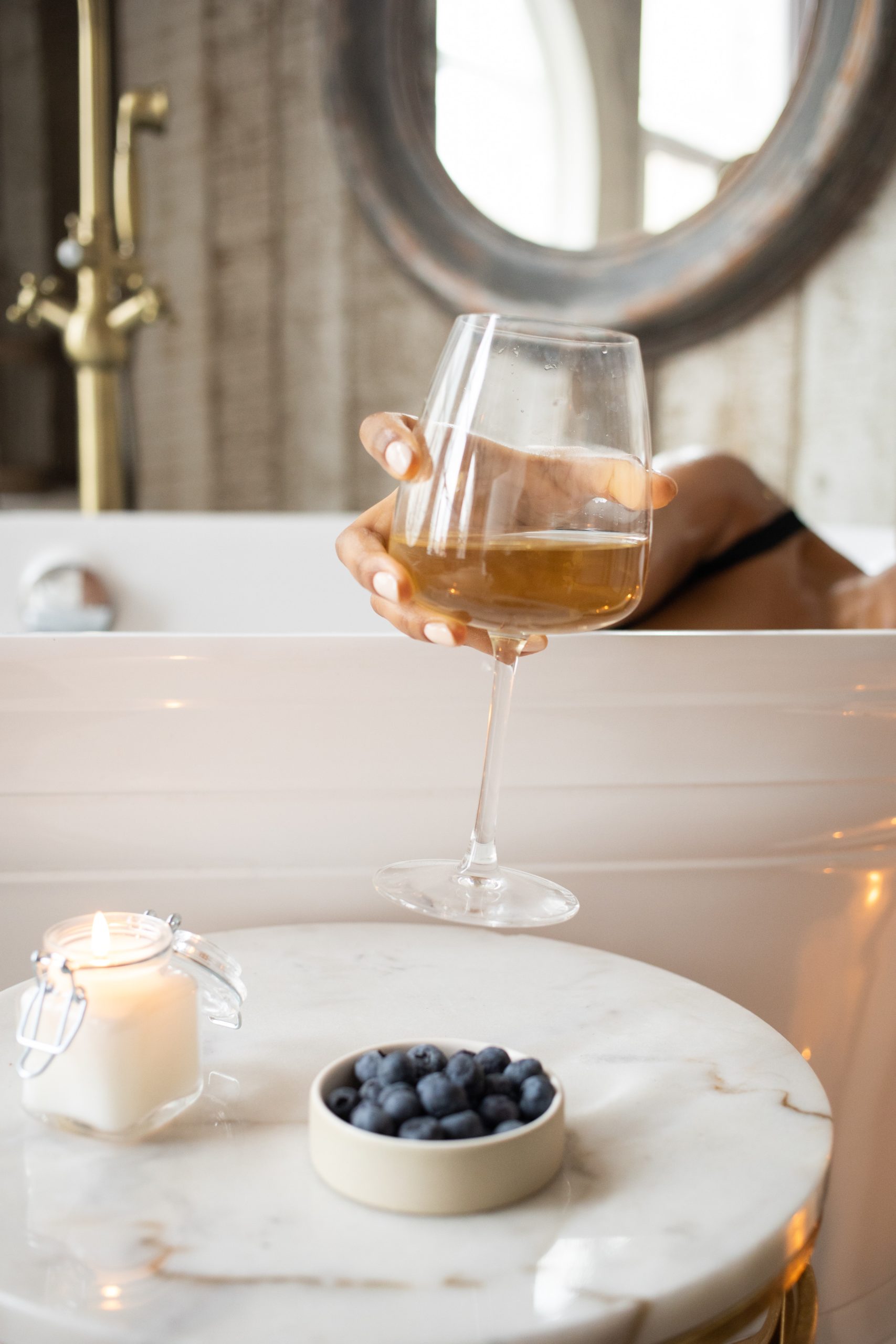 divorcee holding glass of wine in bathtub