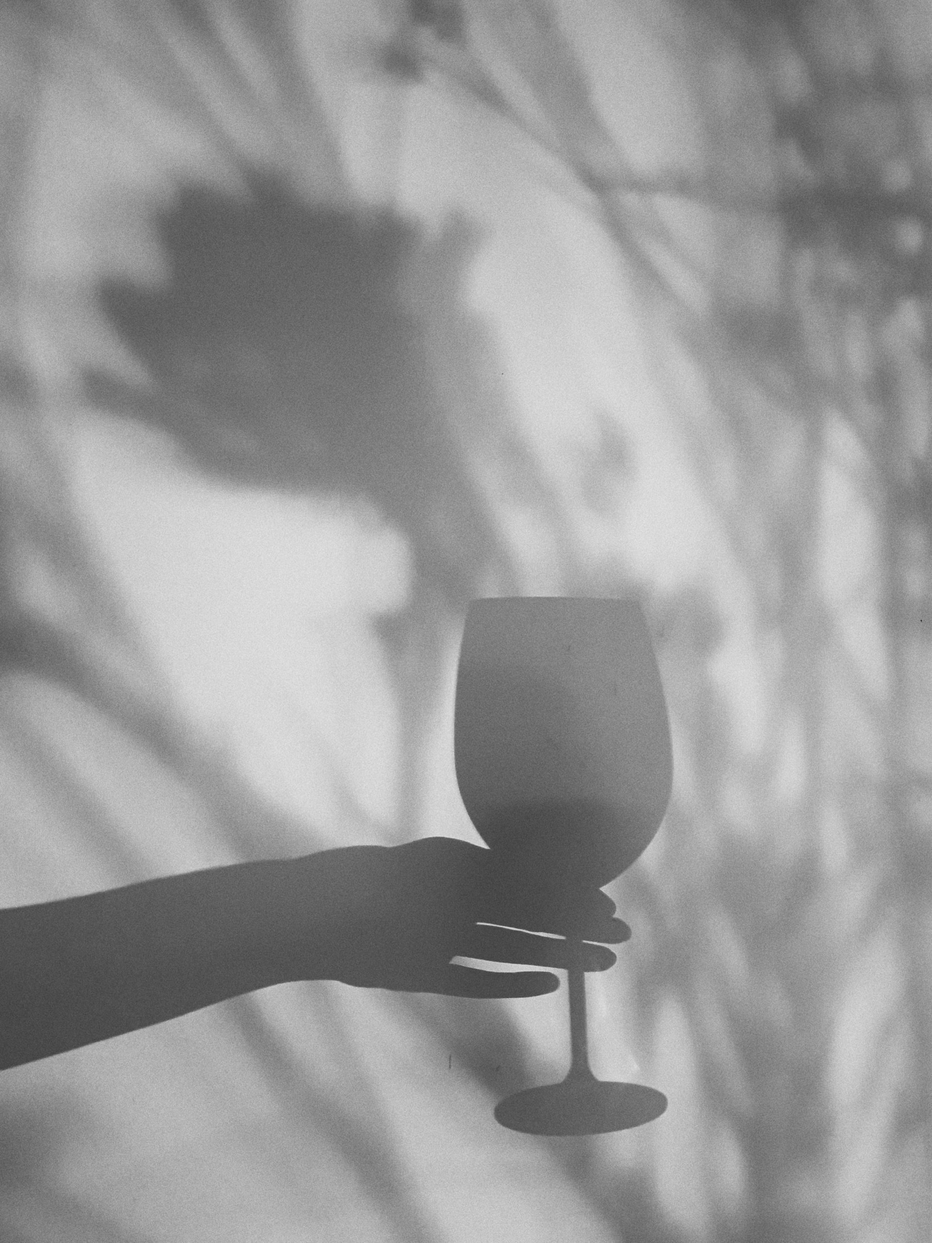 shadow of woman's hand holding a glass of wine